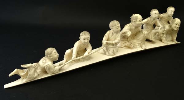 A Meiji period okimono depicting 2 seated figures and 4 boys, one on a hobby horse etc.