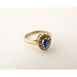 A 9ct gold ring set with central oval blue stone bordered by white stones.