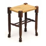 A mid - late 20t C oak twin stretcher stool with envelope rush seat in stretcher stool seagrass