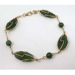 A gold bracelet set with 3 jade like beads and four jade like cabochon in openwork mounts.