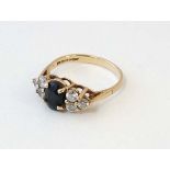 A 9ct gold ring set with dark blue/black stone flanked by white stones.