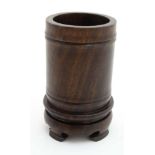 A Chinese cylindrical zitan wood brush pot with integral four foot stand.