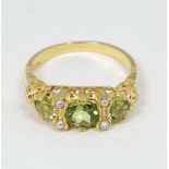 A Silver gilt ring set with three graduated peridot and 6 seed pearls.