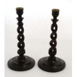 A pair of early 20thC oak open double twist candlesticks with circular stepped bases.