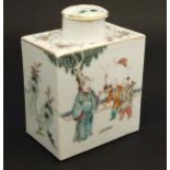 A Chinese famille rose tea caddy decorated in polychrome enamels with figures and bats in a garden