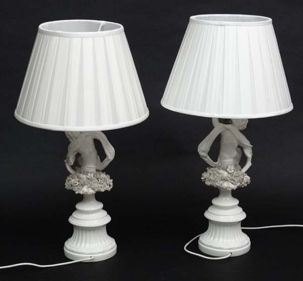 A pair of handed white ceramic table lamps with silk shades, in the form of cherubs with scarves. - Image 2 of 4