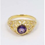 A silver gilt ring set with central amethyst set with numerous seed pearls to the openwork mount