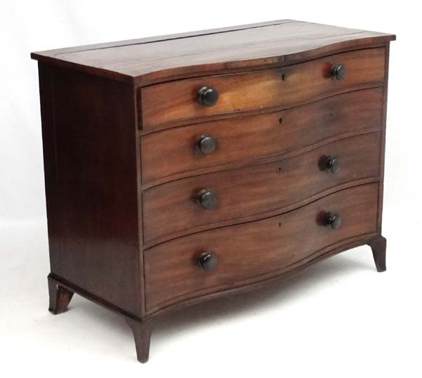 Manner of Gillows : A serpentine fronted mahogany chest of drawers comprising 4 graduate long