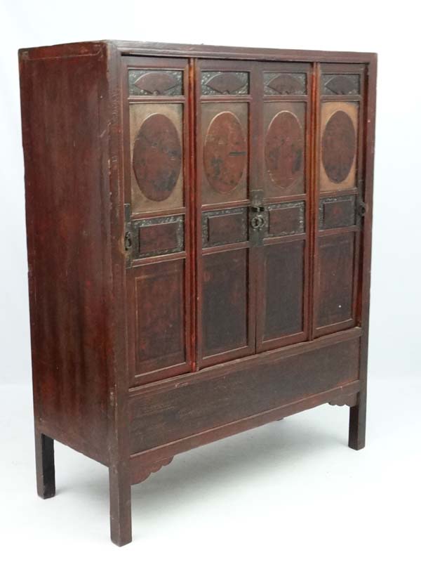 Chinese :a Chinese elm cabinet with painted and lacquered decoration the four doors opening to