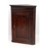 A Georgian Oak hanging corner cupboard with single panelled inlaid and crossbanded door opening to