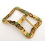 A gilt metal buckle with scroll decoration and set with 6 green stone cabochon.