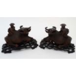 A pair of Chinese carvings formed as children on the backs of water buffaloes on stands ,