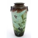 A Moorcroft style twin handled vase decorated with tube lined trumpet flowers in shades of green on