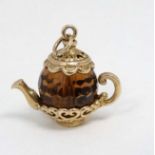 A pendant / charm formed as a miniature teapot the facet amber coloured body with yellow metal