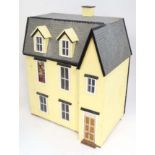 A large mid 20thC three storey wooden dolls house having 6 rooms and pitched roof,