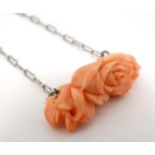 A white metal chain set with carved coral? Pendant of floral form.