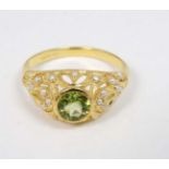 A silver gilt ring set with central peridot set with numerous seed pearls to the openwork mount