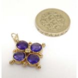 A yellow metal quatreform pendant set with four amethysts and central diamond.