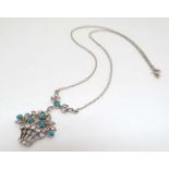 A silver necklace with pendant of flowering basket form set with white stones and turquoise