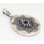 A silver locket of oval form set with seed pearls and amethyst. Marked Sterling.