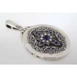An oval locket set with sapphires and seed pearls and with engraved decoration to reverse. .