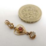 A yellow metal pendant with open work heart decoration set with red and white stones.