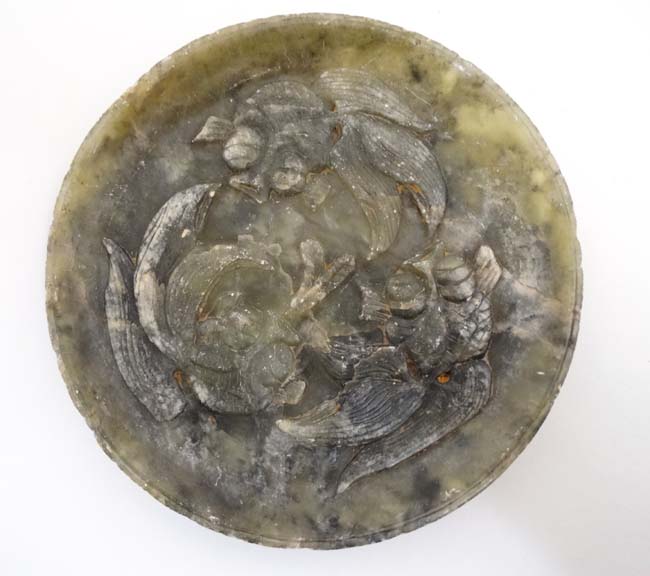 An Oriental jade plate with carved relief depicting 3 gold fish / carp 7 1/8" diameter