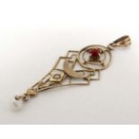 A yellow metal pendant with open work decoration red stone and pearl drop.