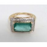 An 18ct gold ring set with central emerald bordered by diamonds.