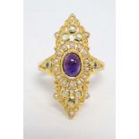 A silver gilt ring set with amethyst cabochon to centre and a profusion of peridot and seed pearls