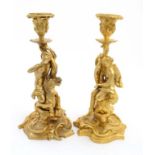 A pair of gilded bronze candlesticks depicting a figure on seahorse and another of a dolphin 1 1/2"