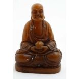 An oriental carved hardstone buddha holding a cylindrical utensil set with many semi precious stone