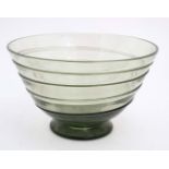 A mid 20thC green glass bowl of stylised conical form with trailed swirl detail and pedestal foot.