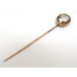 A gilt metal stick pin surmounted by a classical cameo.