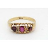 An 18ct gold ring set with central ruby flanked by 2 garnets and white stones