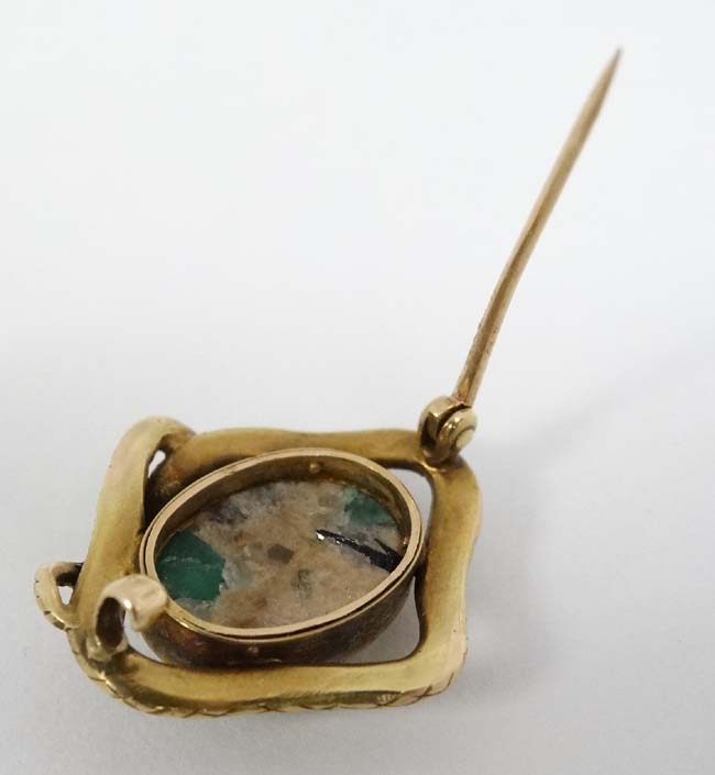 A yellow metal brooch with central hardstone cabochon bordered by a snake formed mount with emerald - Image 2 of 2