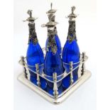 A 21stC silver plate stand containing four blue glass bottles with silver plated mounts having