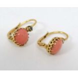 A pair of gilt metal drop earrings set with coral cabochon and white stones.