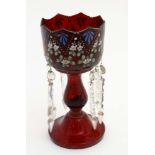 A ruby glass pedestal table lustre with enamelled floral decoration and lustre drops.