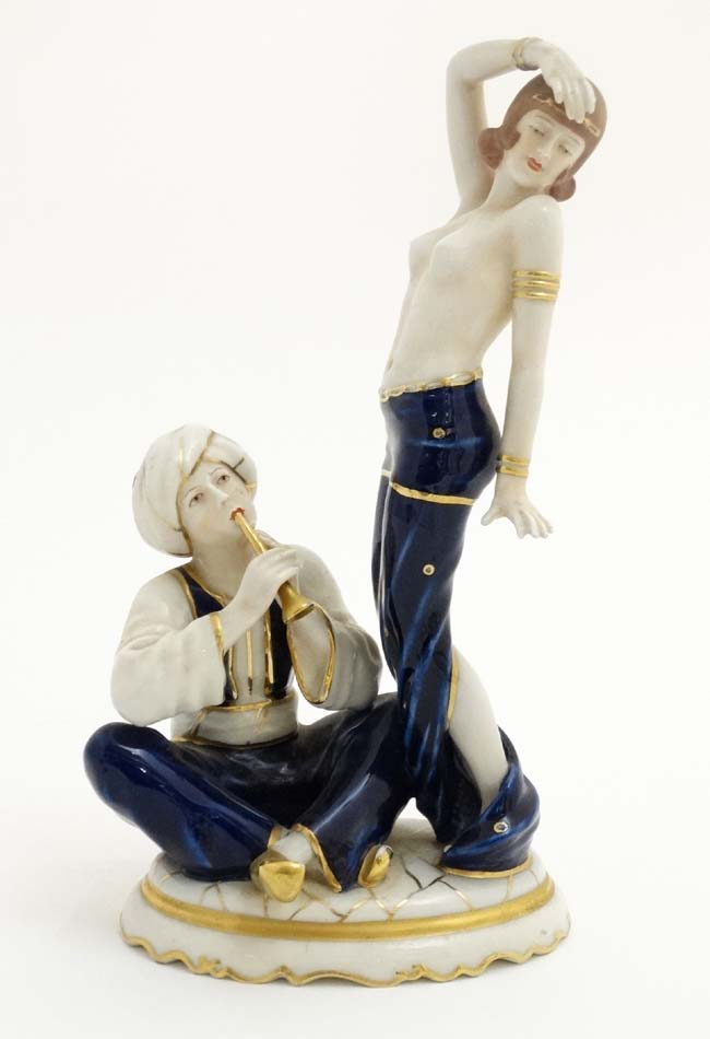 A Royal Dux Art Deco figure group depicting a half naked female in exotic dance pose while a