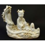 A Chinese Blanc De Chine style figuregroup depicting a female figure seated upon a three clawed