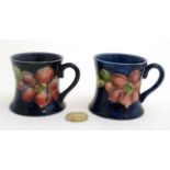 A pair of Moorcroft Miniature ' Clematis ' pattern tankards on a cobalt blue ground ,
