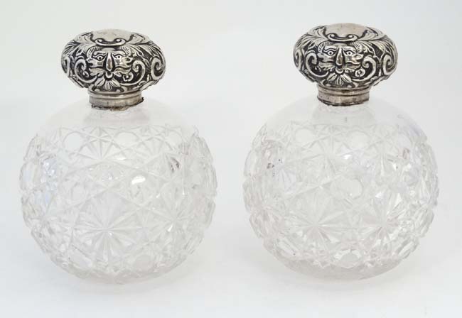 A pair of cut glass scent bottle of spherical form with silver tops hallmarked Chester 1904 maker