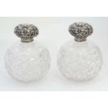 A pair of cut glass scent bottle of spherical form with silver tops hallmarked Chester 1904 maker