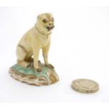 An early 19thC Staffordshire model of a pug seated on a scrolled base wearing gilt collar.