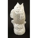 An Oriental pierced Blanc de Chine leaping Koi fish vase, bears indistinct factory stamp to base,