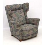 Vintage Retro : A Danish upholstered wing back armchair with show wood feet,