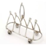 A silver 4 slice toast rack, the dividing bars formed as wish bones.