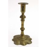 An 18thC petal based brass candlestick with seams to column.