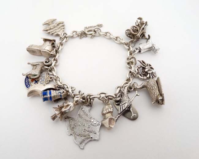 A silver charm bracelet set with 14 various silver and silver plate charms.